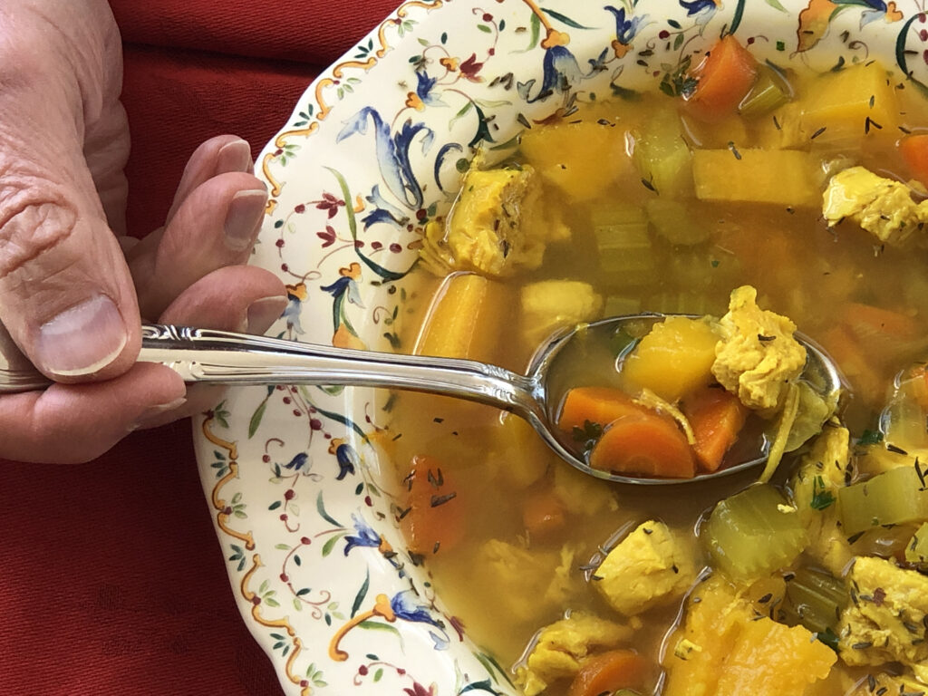 hand dipping a spoonful of Camino Chicken Vegetable Soup shows the delicious and simple ingredients