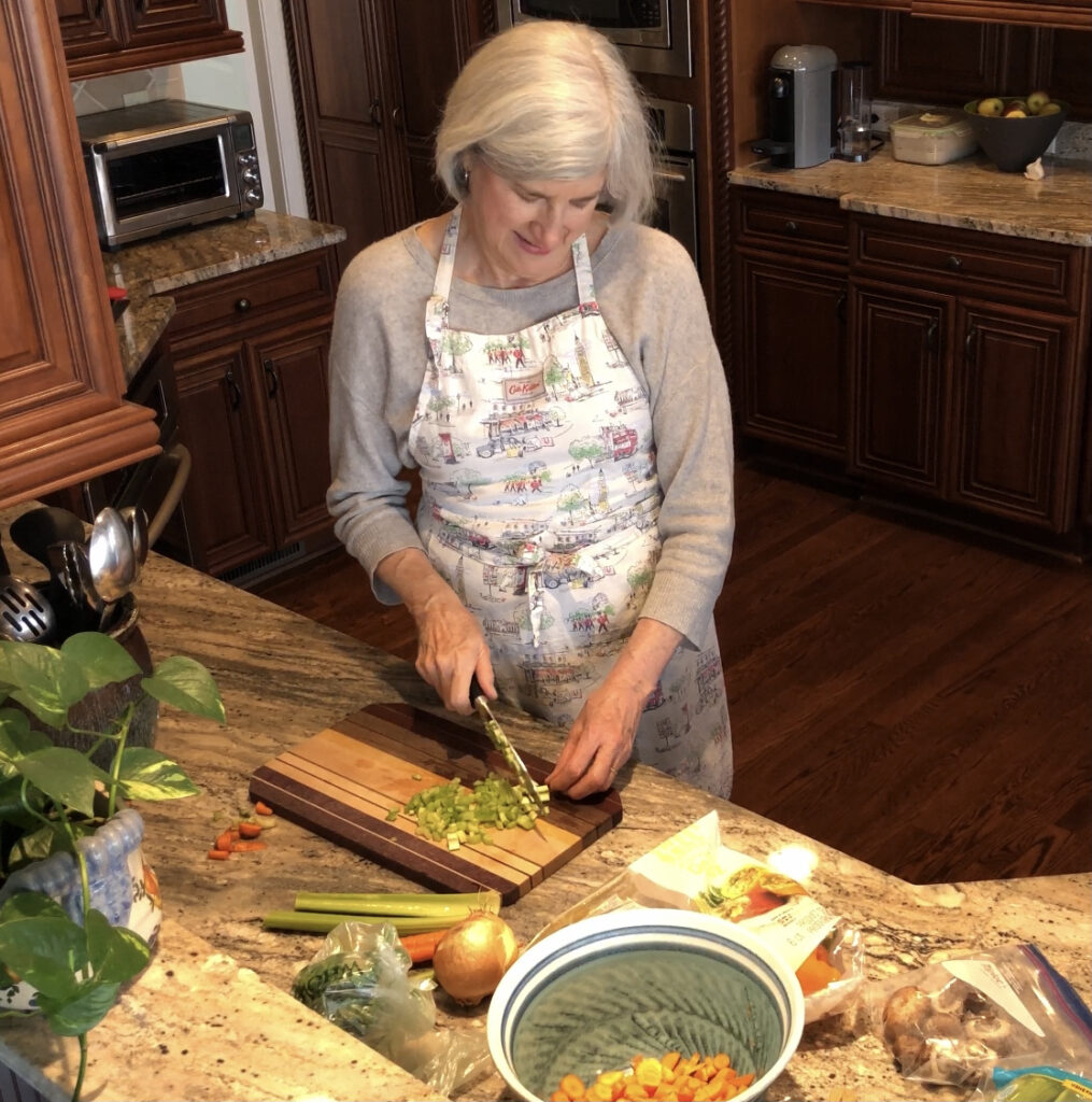 Helen wearing an apron chopping celery for this simple chicken vegetable soup