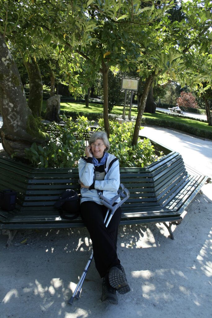 Helen sitting in Alameda Park with crutches, talking on the phone