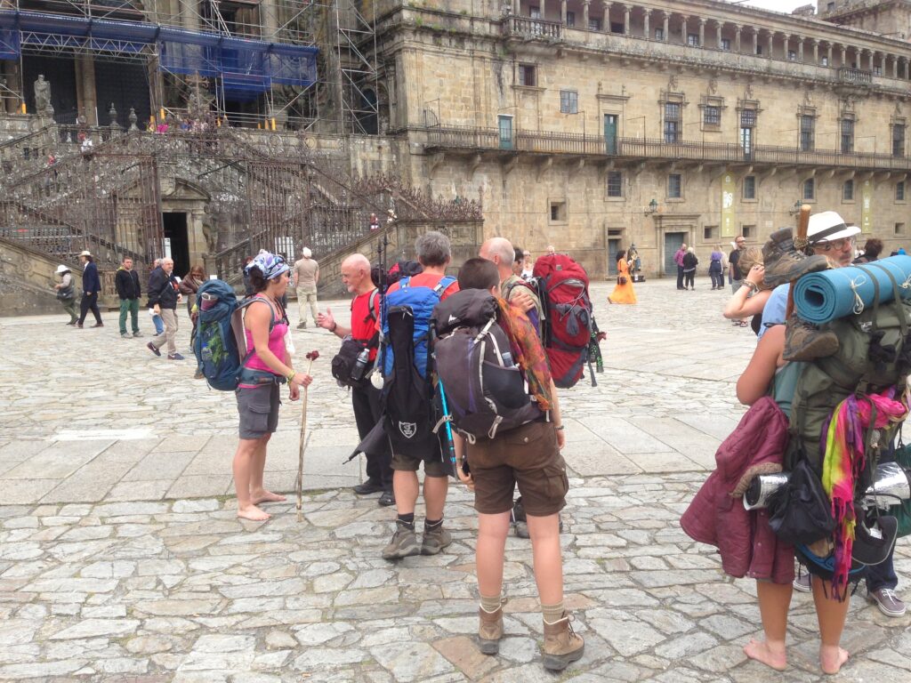 Pilgrims arrive in the Cathedral Plaza with their hiking gear ready to rest and enjoy Santiago