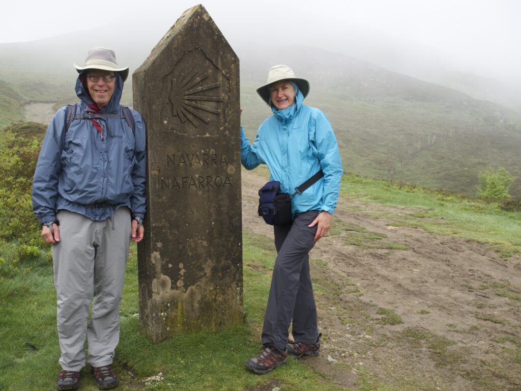 Helen and Wick in hiking gear standing by the stone marking the border between France and Spain