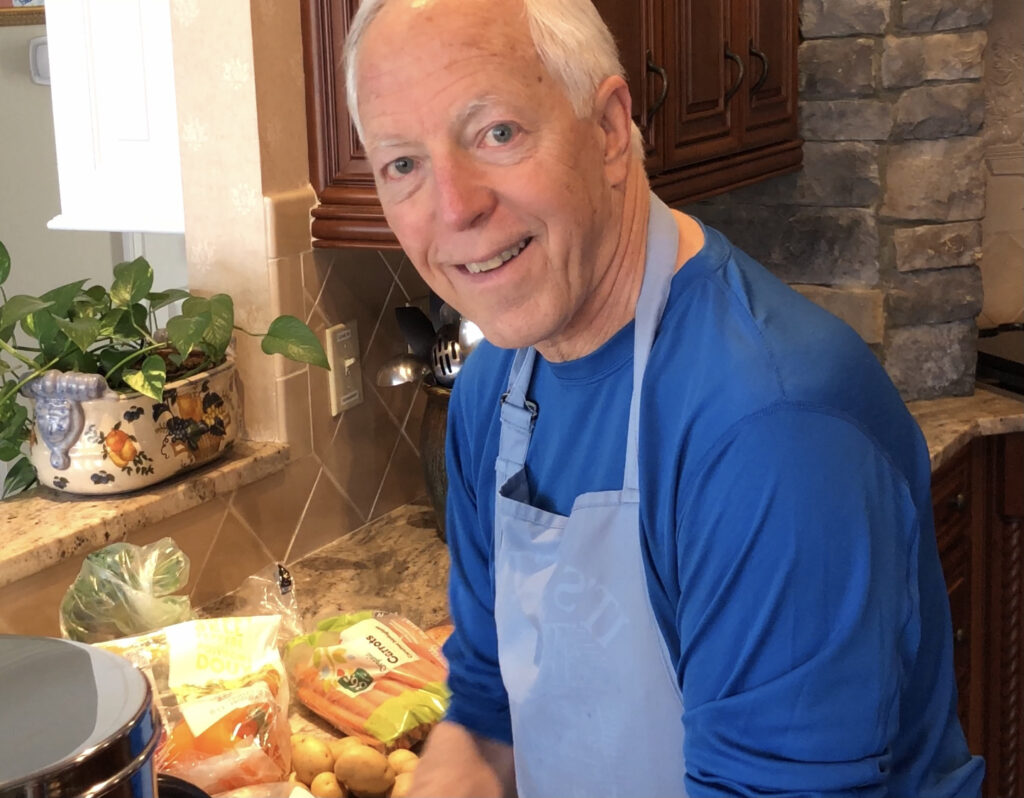 Wick wearing a blue Camino shirt and blue apron preparing the vegetables for the simple soup