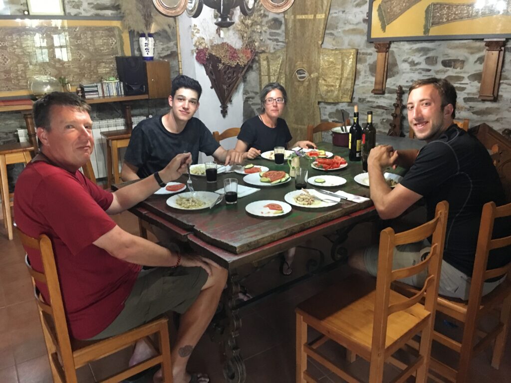 three men and a woman share a meal around a table in a Camino albergue