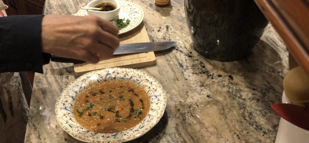 hands sprinkle chopped mint onto bowl of red lentil soup