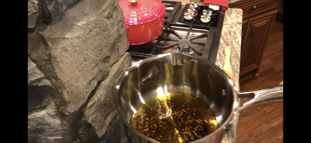 small pot with olive oil and red pepper flakes near a stove