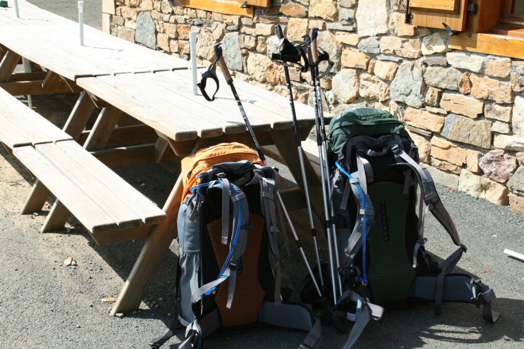 two backpacks leaning on a table with walking poles on the Camino