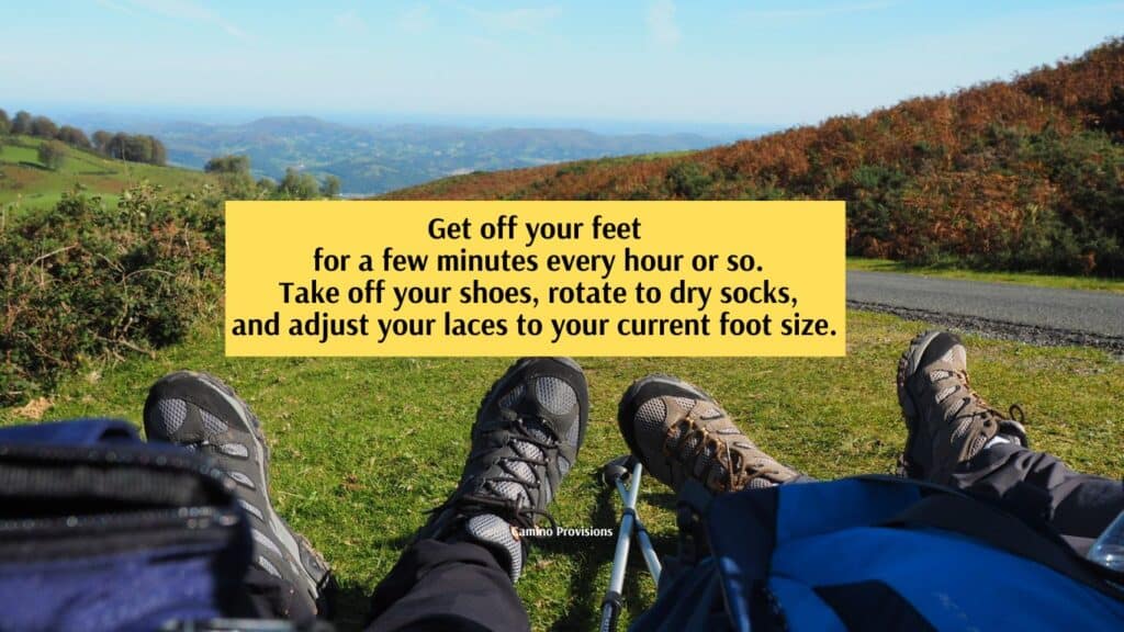 two pairs of feet in hiking shoes at rest on the Camino de Santiago in the Pyrenees by Camino Provisions