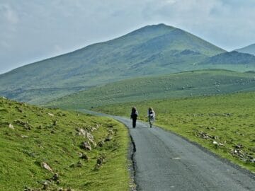 A couple walking the Camino path with Pyrenees mountains in the background