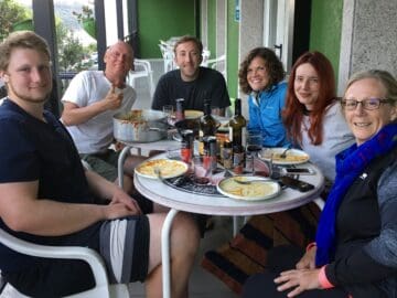 group of Camino pilgrims eat on the porch at their albergue