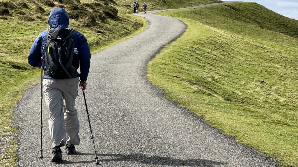 Man hiking up a mountain road with a backpack