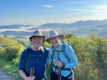 couple wearing hiking clothes and backpacks with mountains in background